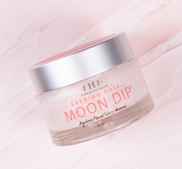 Glass jar of Evening Rose Moon Dip® Ageless Facial Sleep Mousse with Peptides + Retinol | Farmhouse Fresh on a soft pink textured background, showcasing skincare product packaging.
