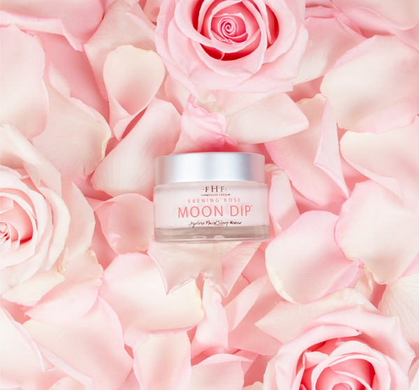 Jar of Evening Rose Moon Dip® Ageless Facial Sleep Mousse with Peptides + Retinol | Farmhouse Fresh surrounded by pink rose petals and fresh pink roses for a skincare and wellness theme.