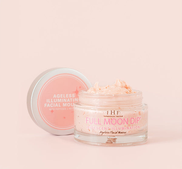 Open jar of Full Moon Dip® Iridescent Illumination Ageless Facial Mousse with Peptides + Retinol | Farmhouse Fresh shown with creamy light pink mousse and product lid beside it on a soft beige background.