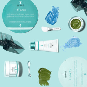 Flat lay of I MASK hydrating hydrogel sheet mask (5 pack) | IMAGE Skincare products including cream, brush, and green and blue skincare product swatches on a light blue background.