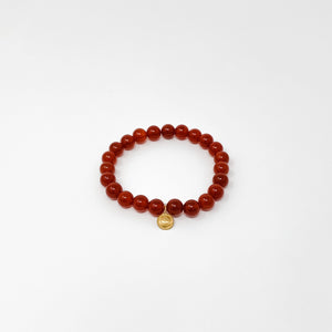 Assorted Satya Bracelets | Satya featuring a single deep red beaded bracelet with a small gold charm on a white background, promoting wellness and style.
