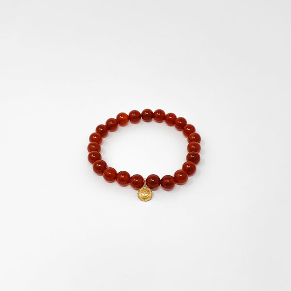Assorted Satya Bracelets | Satya featuring a single deep red beaded bracelet with a small gold charm on a white background, promoting wellness and style.