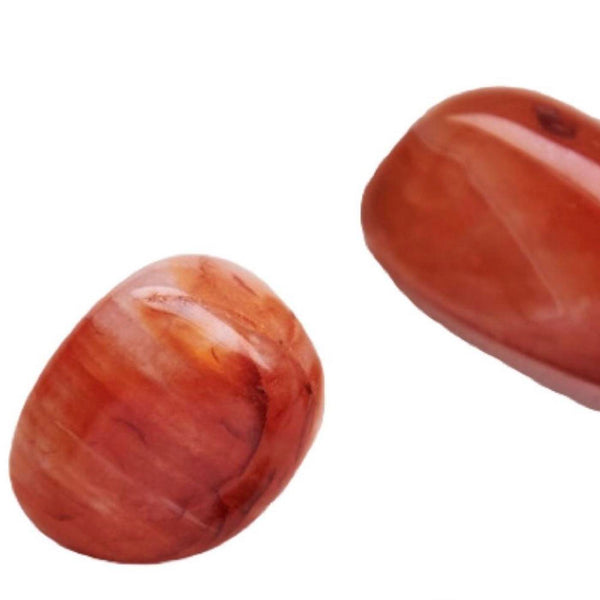 Close-up view of two polished reddish-brown stones associated with the Energy Candle Tin | Aluminate Life, evoking a sense of wellness and natural body care.