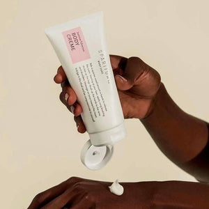 A person applying Jasmine Tuberose BODY CRÈME | Sparitual from a white tube onto their hand, highlighting skincare and body care wellness.