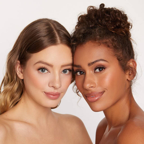 Close-up of two women with flawless skin and natural makeup showcasing eyelash enhancement, promoting Lashies™ - Airy - On The Go | Moxielash beauty and wellness.