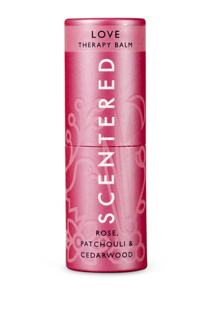Pink cylindrical tube of Love Therapy Balm | Scentered with floral design, featuring rose, patchouli, and cedarwood for skincare and wellness.