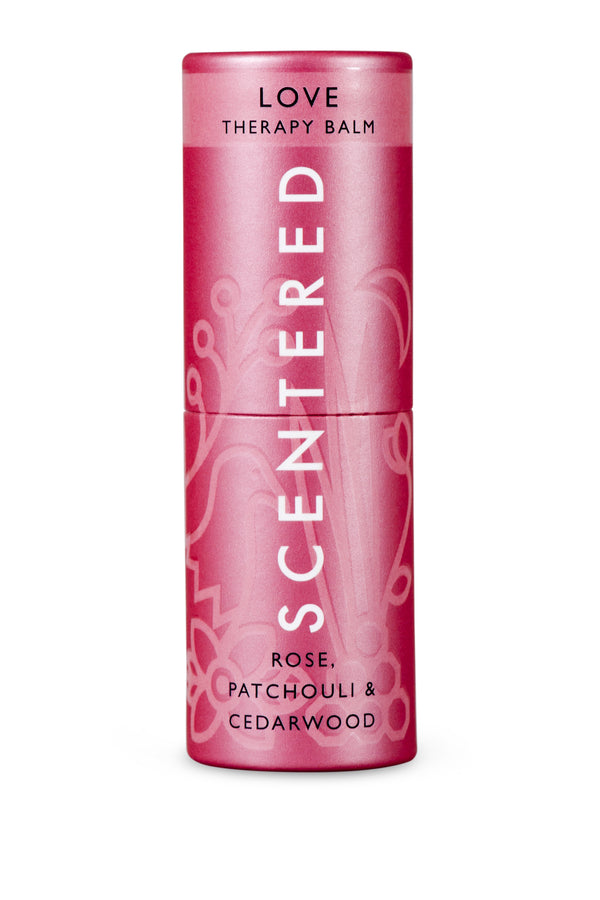 Pink cylindrical tube of Love Therapy Balm | Scentered with floral design, featuring rose, patchouli, and cedarwood for skincare and wellness.