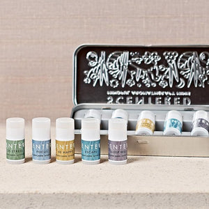 Set of six small aromatherapy inhalers in various pastel shades arranged in front of an open metal tin, featuring the Wellbeing Ritual Aromatherapy Mini Tin | Scentered for wellness and stress relief.