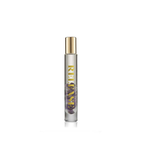 Clear glass rollerball bottle with small purple stones inside and gold cap, labeled Release Essential Oil Rollerball | Aluminate Life, designed for wellness and body care.