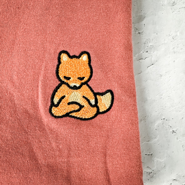 Close-up of a soft pink fabric featuring an embroidered meditating fox patch on the Meditating Fox Comfy Tee | Lucky Owl.