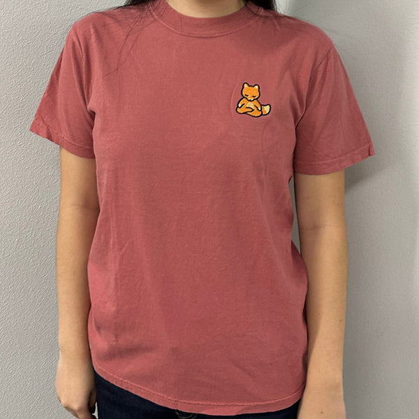 Person wearing a muted rose-colored Meditating Fox Comfy Tee | Lucky Owl with a small embroidered fox meditating on the upper left chest, styled casually against a plain background.