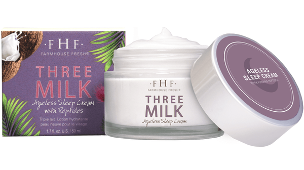 Three Milk Ageless Sleep Cream with Peptides | Farmhouse Fresh in a glass jar with a lid beside its purple and green packaging, showcasing a rich white cream inside for skincare.