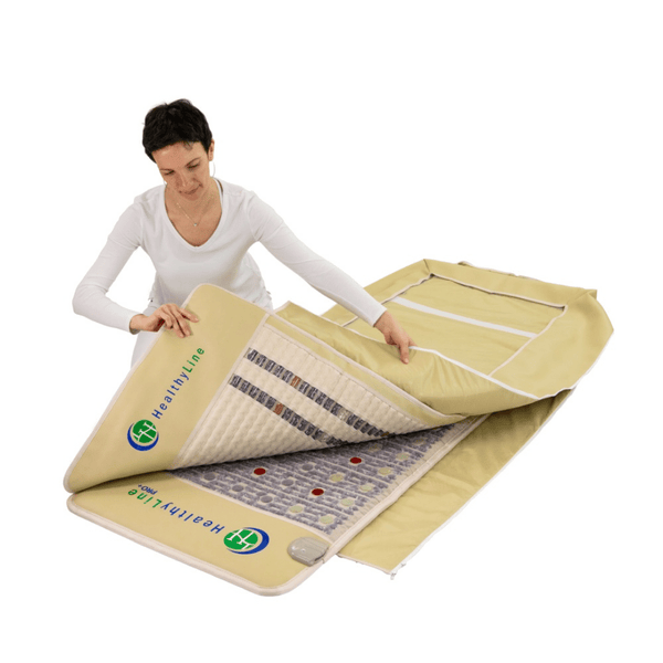 Woman unfolding a beige wellness mat branded HealthyLine, showcasing the inner photon and PEMF therapy layers of the TAJ-Mat™ Full 7224 Firm - Photon PEMF InfraMat Pro® | HealthyLine.