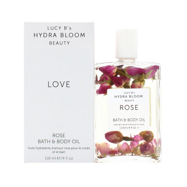 Clear bottle of Rose Bath & Body Oil | Hydra Bloom with visible rosebuds inside, next to its white box packaging, showcasing natural skincare and body care product design.