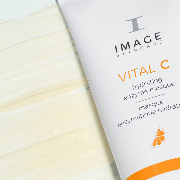 Close-up of a tube of VITAL C hydrating enzyme masque | IMAGE Skincare with a smooth, creamy texture of the masque spread beside it, highlighting skincare and hydration benefits.