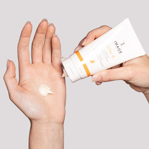 Close-up of a person dispensing creamy white VITAL C hydrating enzyme masque | IMAGE Skincare from a white tube onto their open palm, highlighting skincare use and texture.