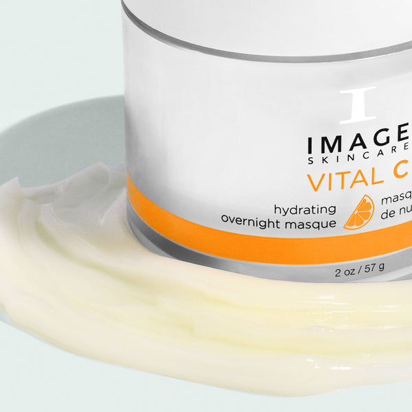 Close-up of a jar of VITAL C hydrating overnight masque | IMAGE Skincare with a smooth creamy texture spread beside it on a light surface.