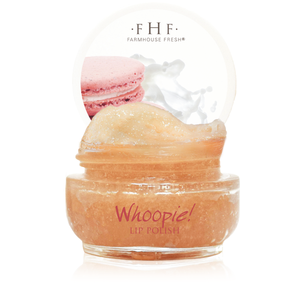 Open jar of Whoopie® Lip Polish | Farmhouse Fresh showing golden exfoliating lip scrub with a soft pink macaron and creamy splash in the background representing smooth, nourishing skincare.