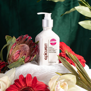 Kukui Coconut After Bath Moisturizer | Epicuren Discovery bottle surrounded by vibrant red, white, and pink flowers on a green background, highlighting skincare and body care.