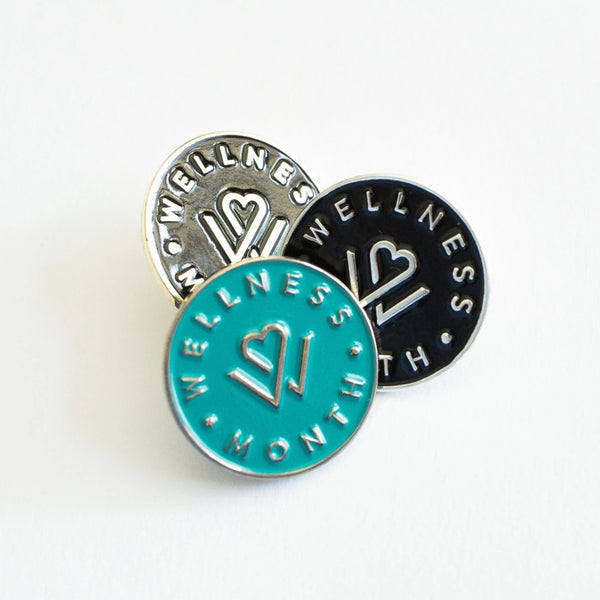Three round Enamel Pins | Wellness Month in turquoise, black, and white, each featuring a heart and wellness emblem in silver metal finish.