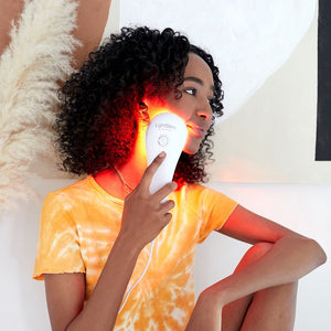 Woman using the LightStim For Wrinkles | LightStim device on her cheek, showcasing skincare and wellness with red light therapy for facial rejuvenation.