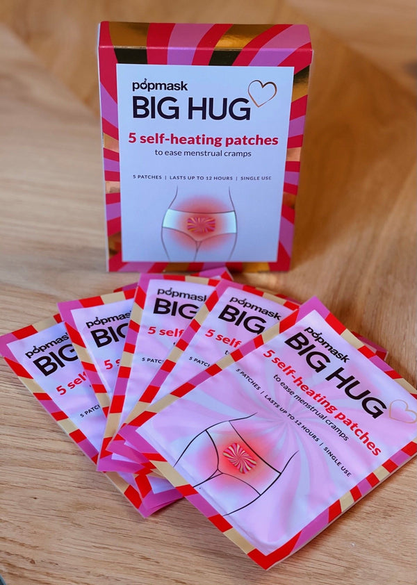 Big Hug - 5 Pack | Popmask self-heating patches designed to ease menstrual cramps, featuring single-use patches that last up to 12 hours, displayed on a wooden surface.